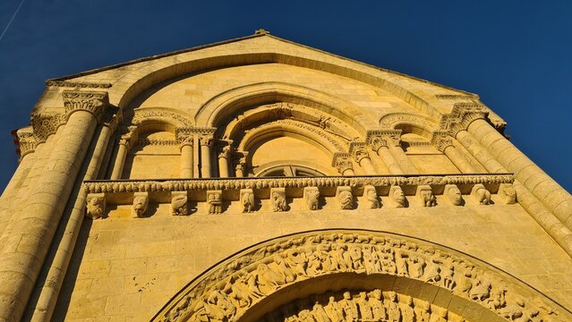 La fa&ccedil;ade sud de l'&eacute;glise Saint-Pierre d'Aulnay de Saintonge et son magnifique portail roman illumin&eacute;s par la lumi&egrave;re du soleil couchant (France)