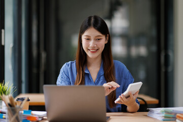 Fototapeta premium Asian business woman smiling calculating finances in office