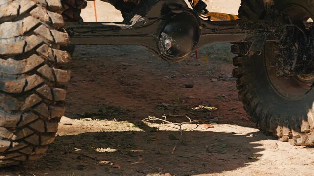 A close-up of a muddy SUV tire and suspension. Mud covers the large treads and wheel rim. Concept of motorsports, adventure, and extreme driving