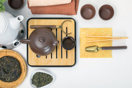 Yixing teapot on bamboo chaban with tea accessories for traditional ceremony. Flat lay of puerh tea leaves, cup and chahe on wooden table. Healthy lifestyle and wellness concept