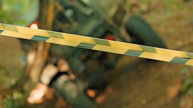 Shallow depth of field, focusing on yellow and black caution tape. A blurred all-terrain vehicle in the forest during an extreme sports competition