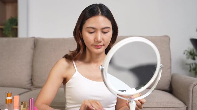 Asian beauty influencer recording makeup tutorial at home with smartphone, skincare and cosmetics content creator livestream.