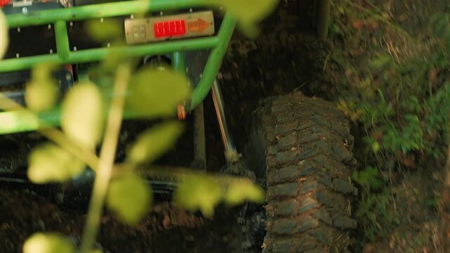 A close-up of a large off-road tire cutting into the mud. Power and speed. A mud tire on rough terrain during an extreme competition. Natural light in the forest