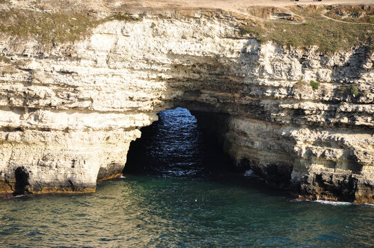 Geological formation. Mysterious entrance to the grotto on a wild beach. Natural beauty and coastal tourism.