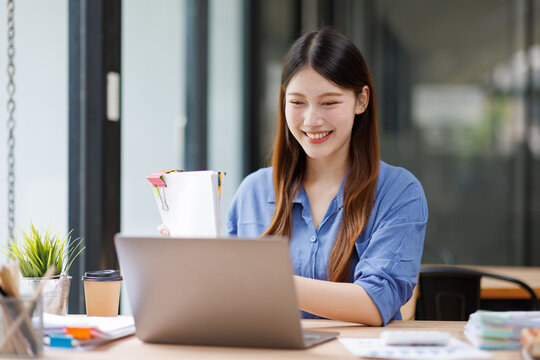 Asian working woman smiling with laptop at office