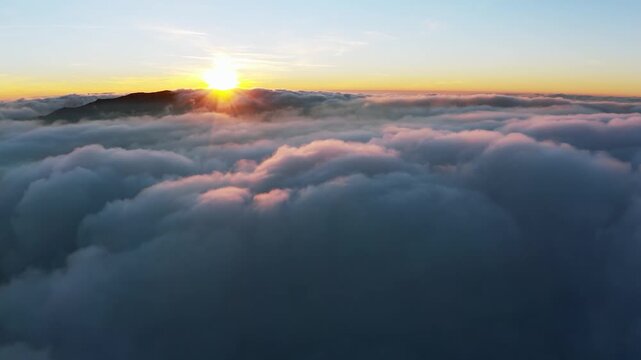 Thick layer of white clouds above mountains at sunrise