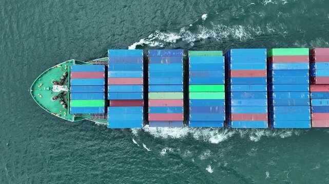 container ship fully loaded with colorful cargo containers being assisted by tugboats in the open sea. Concept of global maritime logistics, international trade, and heavy shipping operations.	
