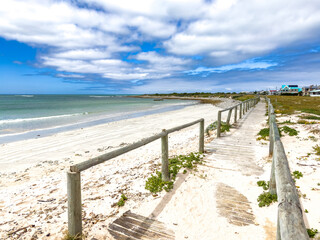 Fototapeta premium Tranquil coastline landscape with azure sky, sand, rocks, and gentle waves