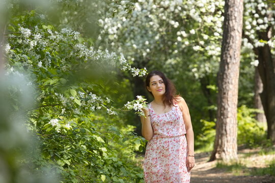 Portrait of a young woman in a spring park. A beautiful woman stands near a blossoming tree. 