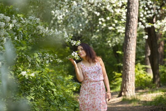 Portrait of a young woman in a spring park. A beautiful woman stands near a blossoming tree. 