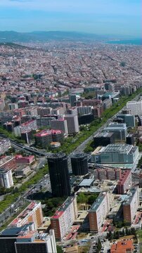 Vertical video 4K aerial view of Barcelona's Avinguda Diagonal with CaixaBank towers, L'Illa shopping centre, Les Corts district stretching to Collserola hills and Mediterranean coastline.