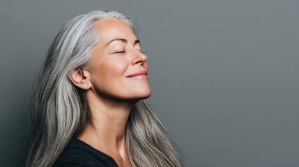 Fototapeta premium Portrait of a serene older woman with closed eyes and flowing silver hair