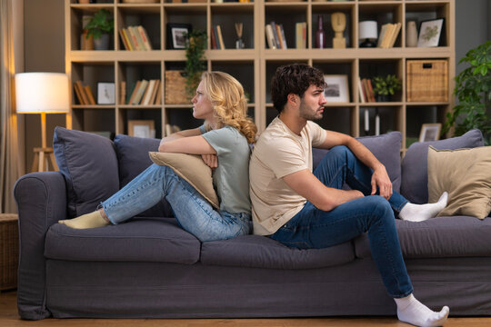 Couple having conflict sitting back to back on sofa