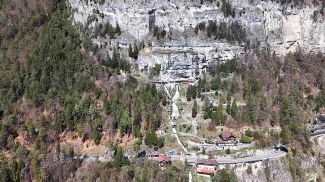 Aerial View of Saint Beatus Caves Entrance with Waterfall and Historic Buildings, Lake Thun, Switzerland