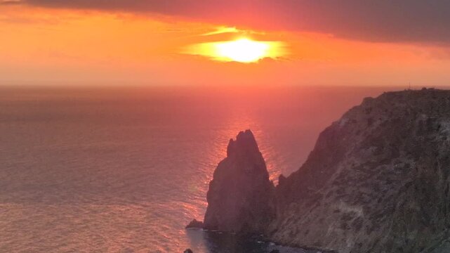 Sunset, Ocean, Cliffs dramatic sea stack in golden hour with vibrant sky reflecting on calm water