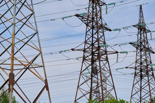 Power lines stretch across a landscape under a clear blue sky creating an industrial scene