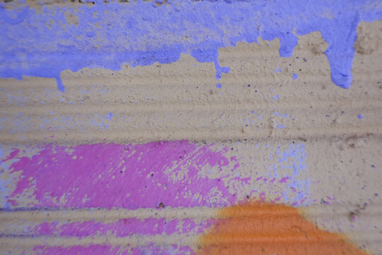 Messy paint strokes on old grunge brick wall. Pink, purple, yellow, black color drips, flows, streaks of paint and paint sprays