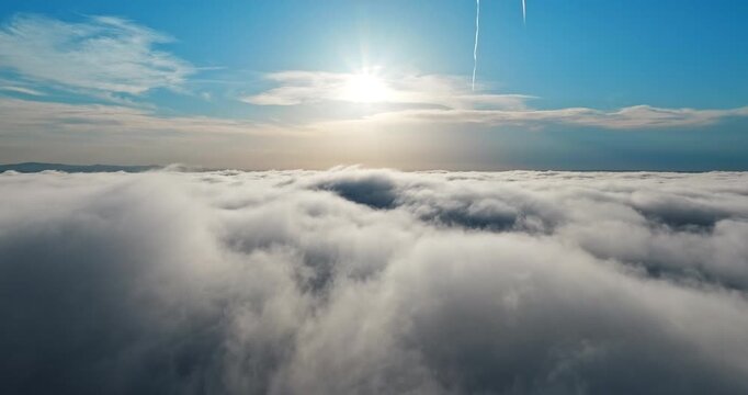 Sun shining over white fog aerial. High altitude drone shot rising through clouds dreamy atmosphere blue sky. Summer vacation concept nature beauty exploration high angle scenic landscape.