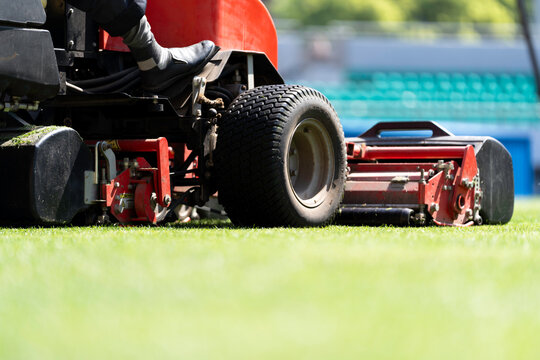 Workers are using a lawnmower to maintain the football pitch