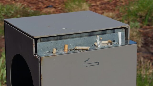 Neglected concrete area with trash. Grungy concrete background featuring scattered debris. Slow motion imagery highlighting rough texture of abandoned outdoor cigarette trash area