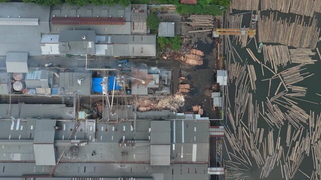 Aerial view of sawmill processing plant with timber logs floating on water