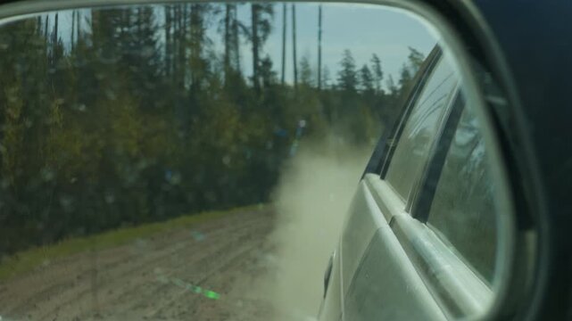Dusty road scene. Dust particles drifting slowly across gravel pathway in cautious setting. Dust gently moving across rough gravel surface with subdued forest background and safety tone