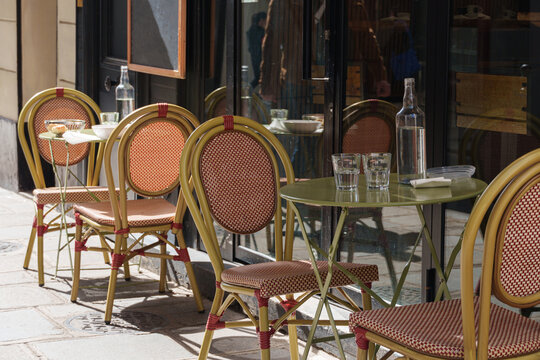 Empty Paris cafe table with woven chairs and glassware on quiet street corner in Paris