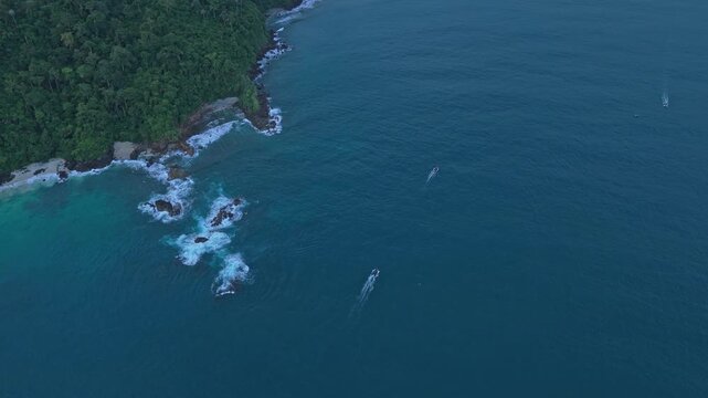 Aerial view of tropical coastline with boats cruising on the ocean