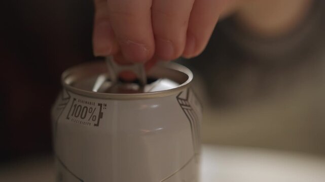 Kid uncaps can. Child slowly presses tab. Young child carefully opens metal container. Young person gently removes lid from can. Small child cautiously unscrews lid of metal can for access