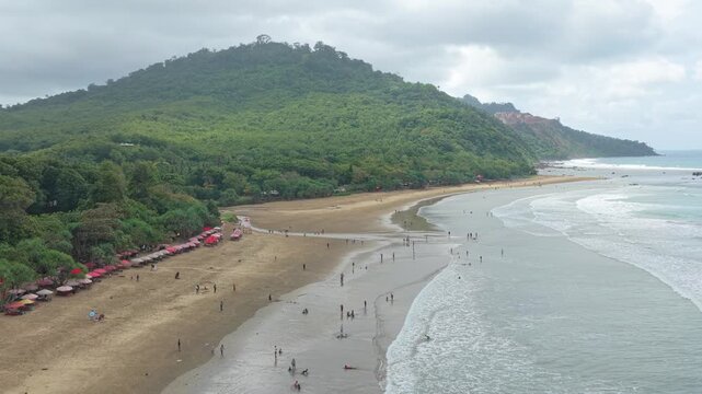 People enjoying a tropical beach in java on a cloudy day