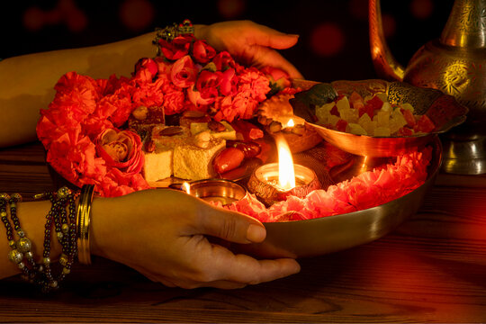 Traditional Indian puja thali with diya oil lamps, sweets, flowers, and offerings in warm festive lighting. Cultural and religious ceremony concept, Diwali celebration, spirituality, and ritual.