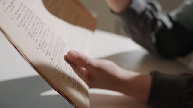 Closeup hands flipping vintage paper pages, sunlit table with glass of tea, delicate fingertips explore worn text, archival reading mood, librarian research role, warm shadow and tactile texture