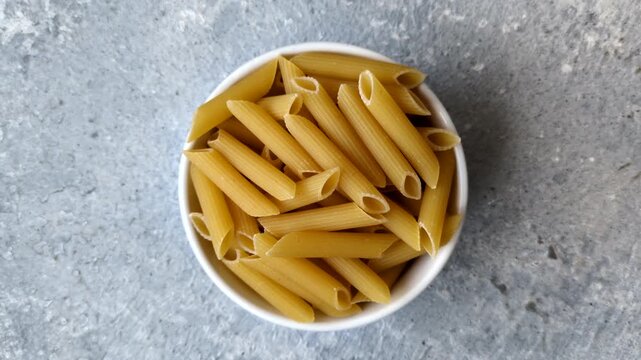 Italian uncooked dry penne regate pasta ready for cooking. Dry penne pasta as a food background for your design.