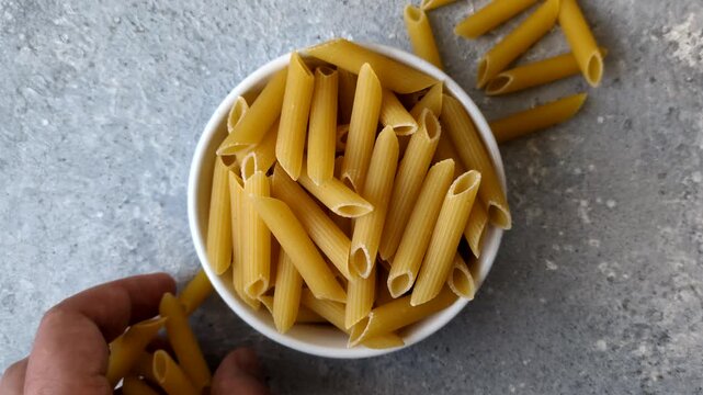 Italian uncooked dry penne regate pasta ready for cooking. Dry penne pasta as a food background for your design.