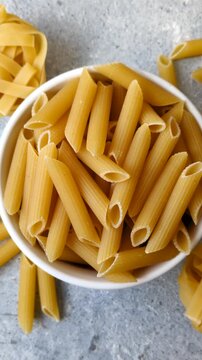 Italian uncooked dry penne regate pasta ready for cooking. Dry penne pasta as a food background for your design.