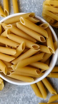 Italian uncooked dry penne regate pasta ready for cooking. Dry penne pasta as a food background for your design.