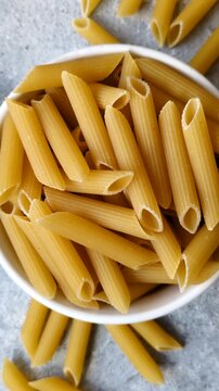 Italian uncooked dry penne regate pasta ready for cooking. Dry penne pasta as a food background for your design.