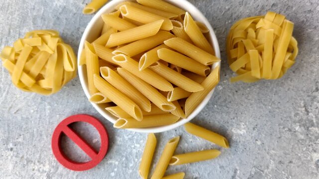 Italian uncooked dry penne regatta pasta with a gluten prohibition sign. The gluten prohibition sign as a background for your design.