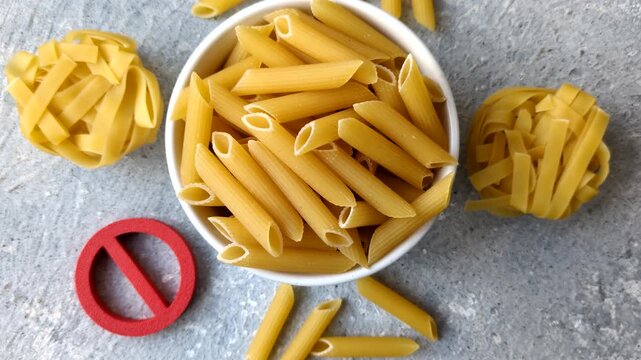Italian uncooked dry penne regatta pasta with a gluten prohibition sign. The gluten prohibition sign as a background for your design.