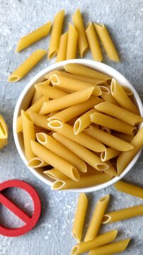 Italian uncooked dry penne regatta pasta with a gluten prohibition sign. The gluten prohibition sign as a background for your design.