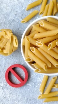 Italian uncooked dry penne regatta pasta with a gluten prohibition sign. The gluten prohibition sign as a background for your design.