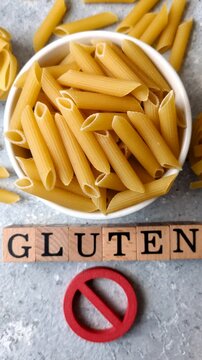 Italian uncooked dry penne regatta pasta with a gluten prohibition sign. The gluten prohibition sign as a background for your design.