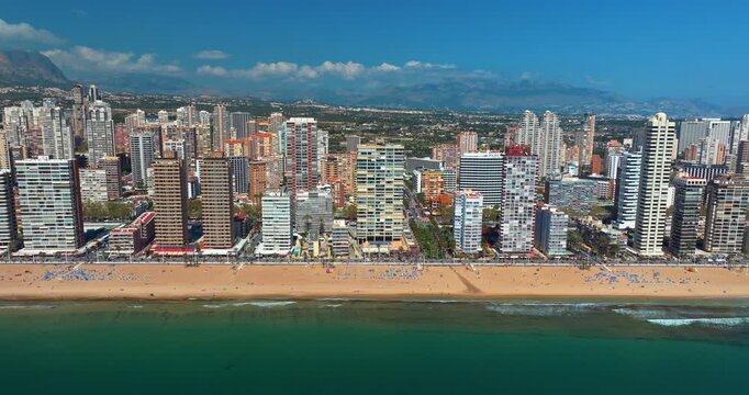 Frontal aerial view of Benidorm skyline Spain featuring high rise buildings along Mediterranean coast. Drone panorama of Levante beach and modern skyscrapers during summer travel.