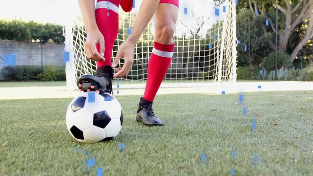 Teen soccer player securing ball under foot tying cleat laces while blue overlay appearing readying
