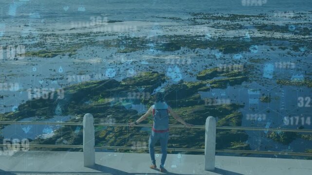 Woman walker walking to rail, leaning, viewing tide pools while blue data overlay animating tech