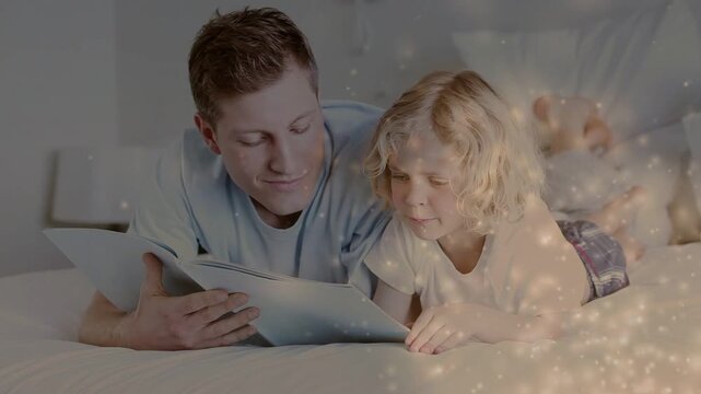 Father and child on bed, father tilting book for learning, sparkles drifting right, child smiling