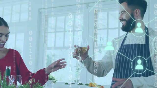 Man in apron serving wine, woman accepting and sharing, talking in kitchen, tech overlay appearing