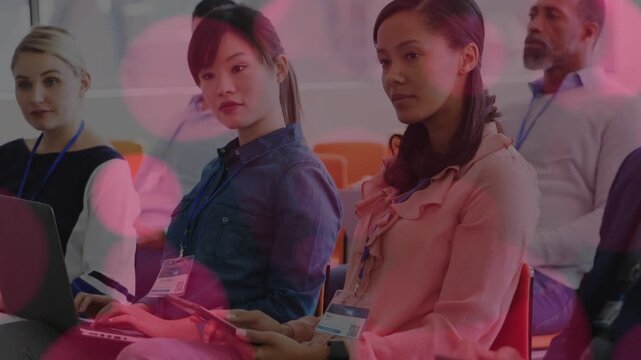 Three women attendees using devices in business conference, pink overlay appearing, hiding faces