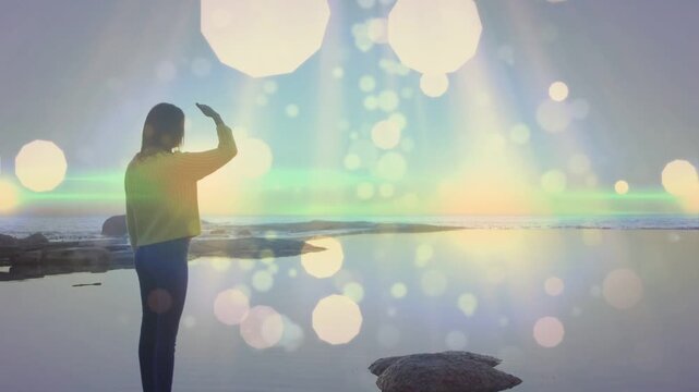 Woman turning shading eyes as sun nearing scanning horizon bokeh and flare round her for health