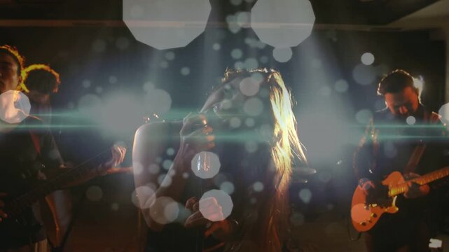 Singer starting music, bending to mic, whipping hair, settling back while bokeh pulsing over faces